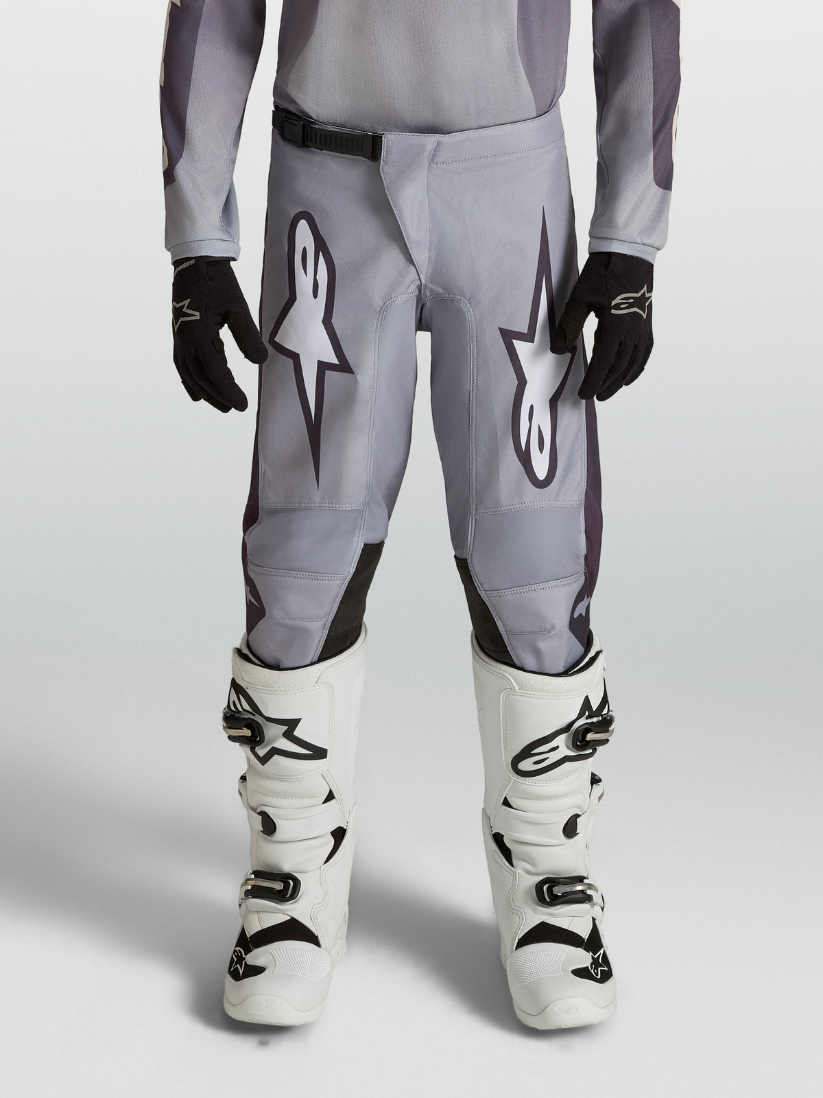 Alpinestars Youth Fluid Amber Pants, durable grey and black motocross pants for young riders in an off-road setting.