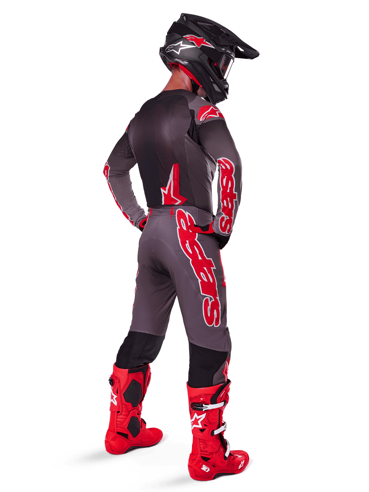 Motocross rider wearing 2025 Supertech Lipan Jersey, Smoke Bright Red, viewed from behind with matching grey and red pants, bright red boots, black helmet with red accents and red goggles, coordinated pro-level gear set for off-road racing