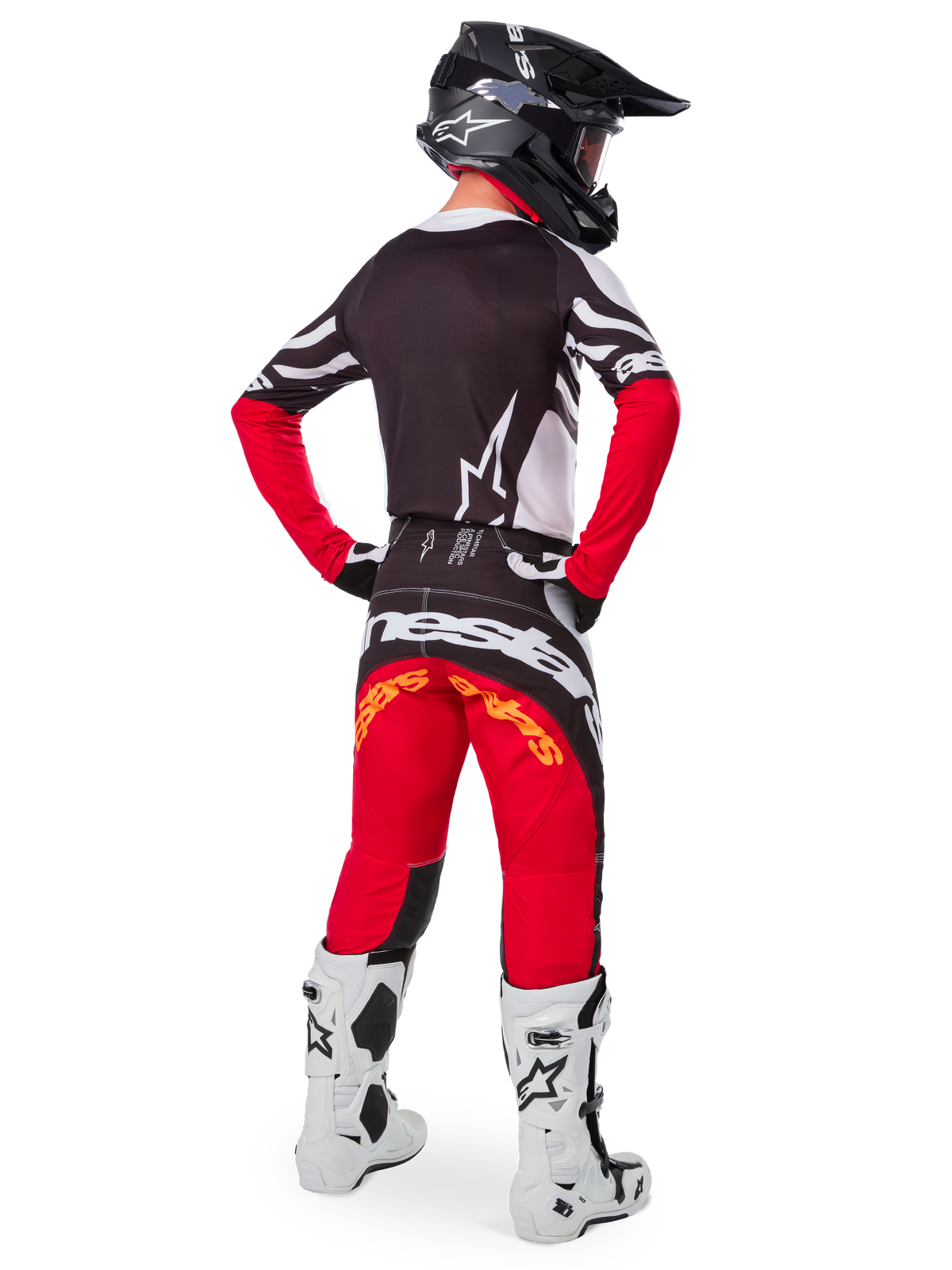 Motocross rider from the rear wearing the Alpinestars Limited Edition Techstar Deep Jersey in Black White High Red, featuring a black back with white star logo and red sleeves, paired with matching red and black pants, white and black boots, and a black helmet for a complete off-road racing outfit.