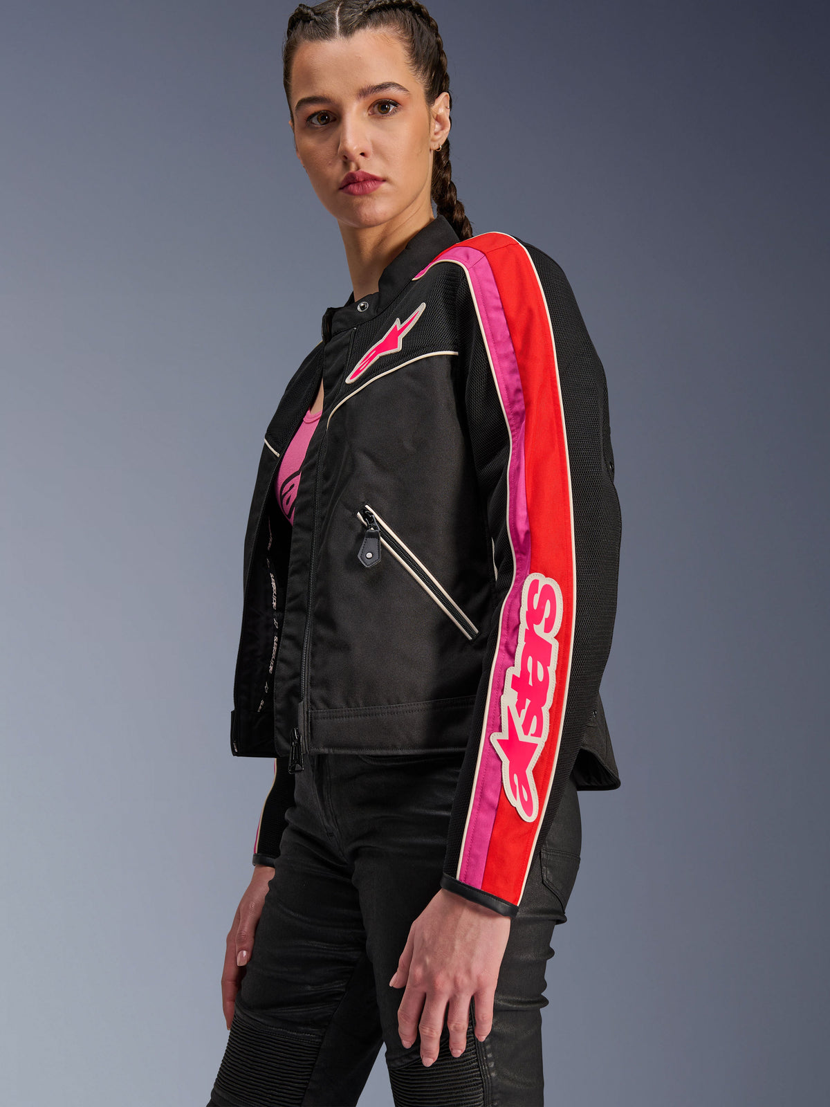 Alpinestars Woman Stella T-Dyno Air Jacket, Women's Motorcycle Jacket, Black with Bright Red and Fuchsia accents, worn with black pants, featuring pink Astars logo on the chest and sleeve, tailored biker fit with mesh panels for ventilation.