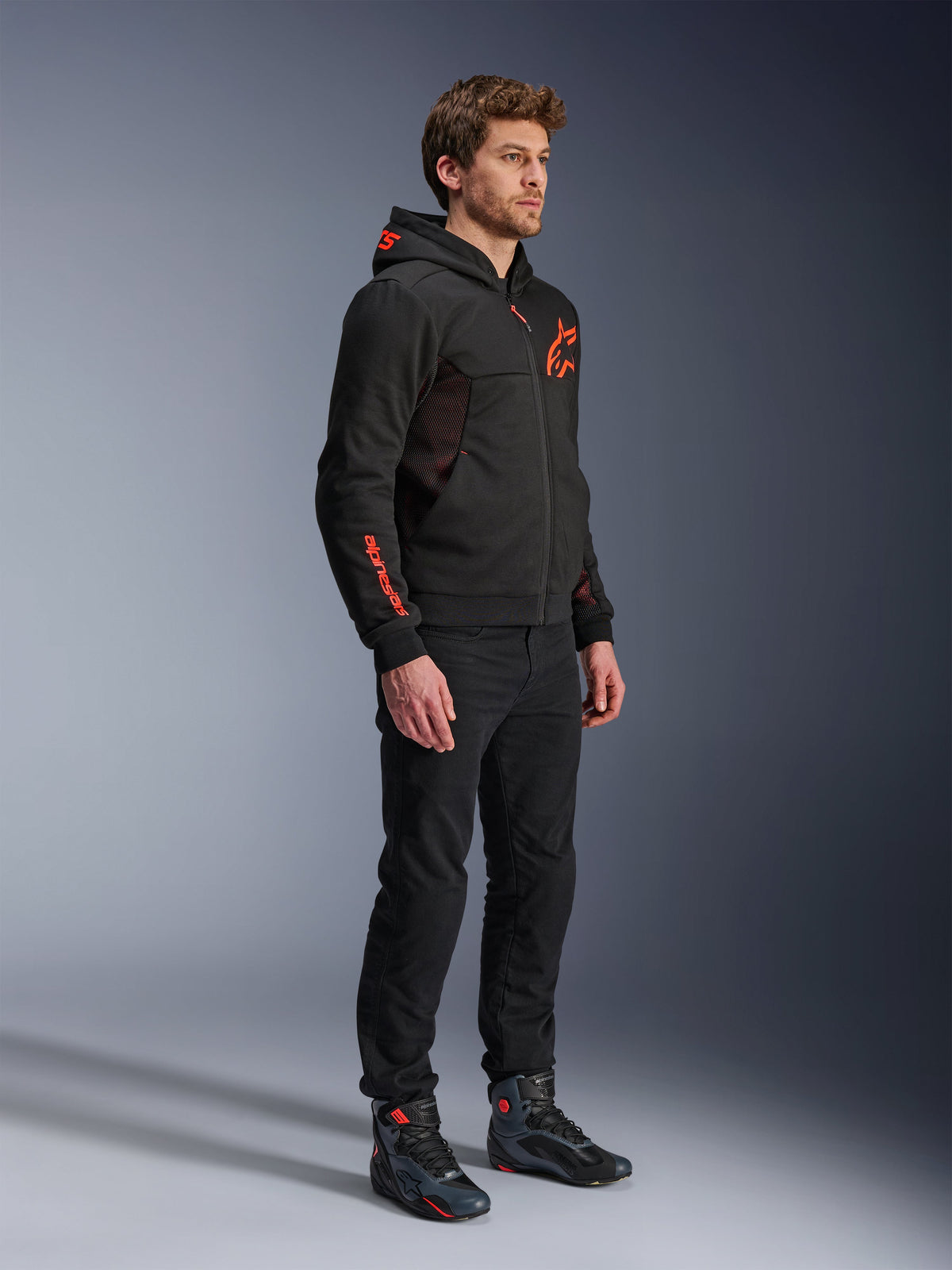 Alpinestars Chrome Air Sport Hoodie, Black Red Fluo, urban riding jacket with tech fleece, worn with black pants and motorcycle boots, featuring mesh ventilation panels and red fluorescent logos on the chest and sleeve.