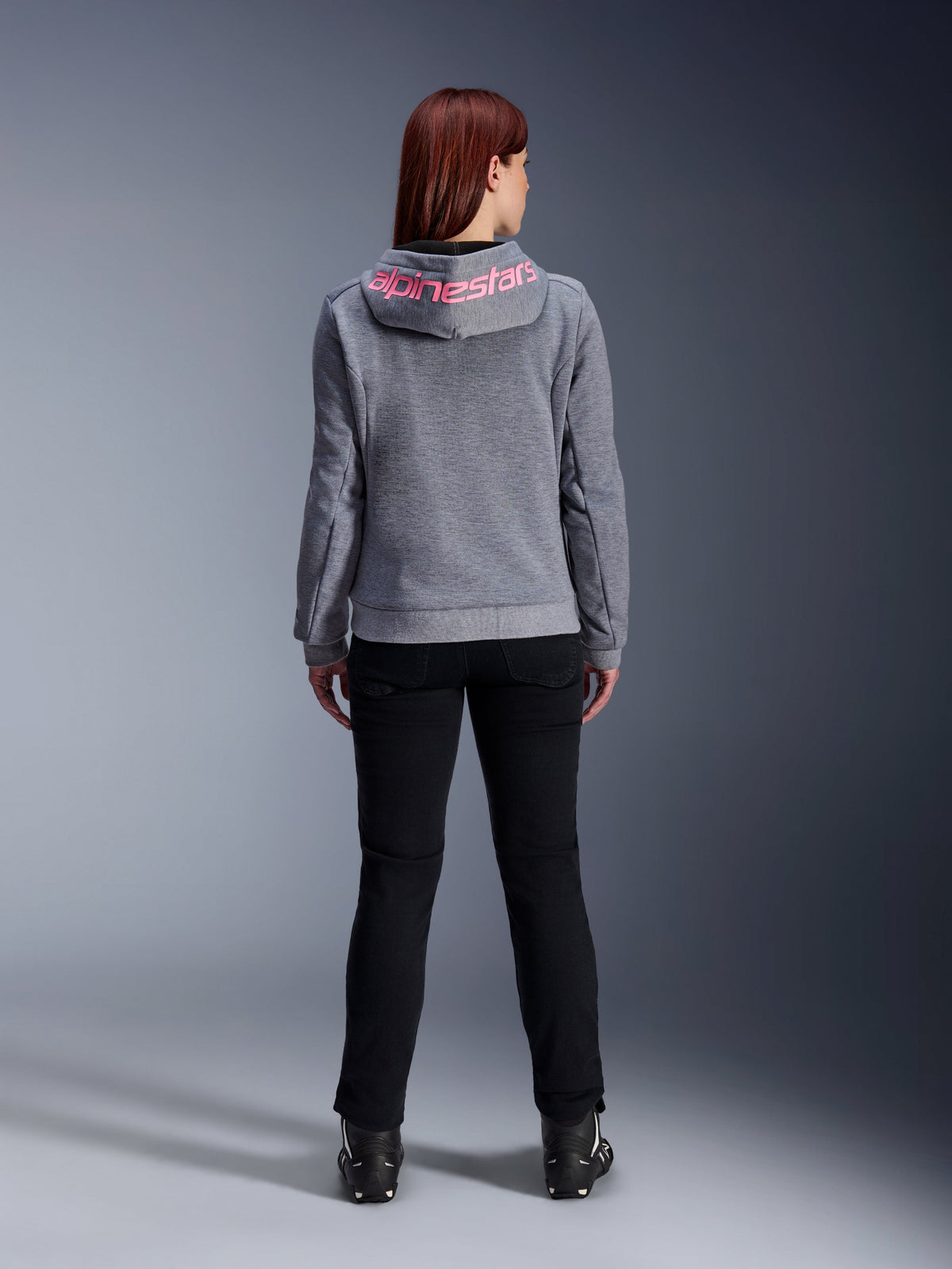 Alpinestars Stella Chrome V2 Sport Hoodie, Women's Motorcycle Hoodie, Gray Heather and Pink Fluo, back view showing pink Alpinestars logo on the hood, worn with black riding pants and boots, casual motorcycle apparel for women