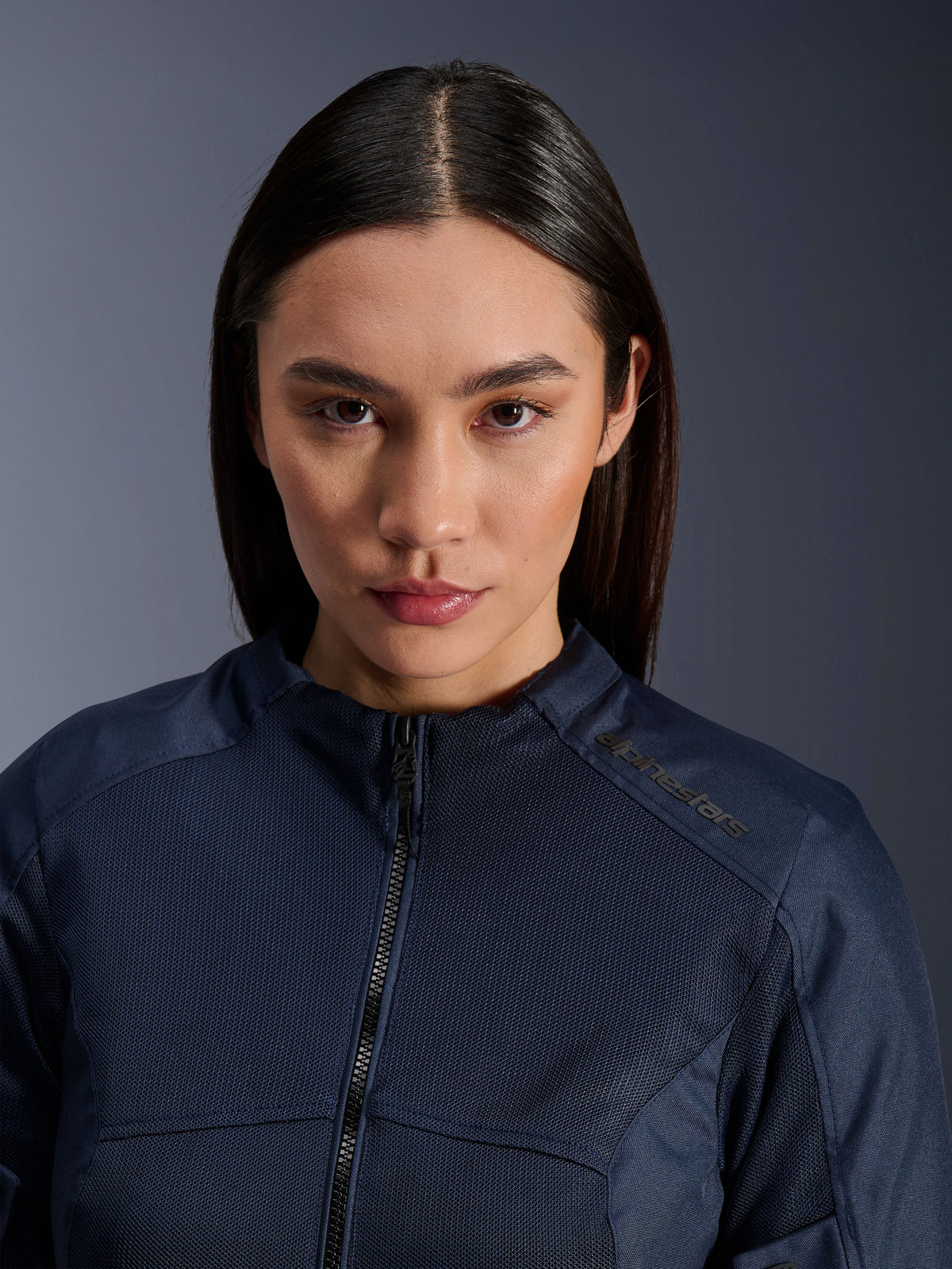 Female model wearing the Alpinestars Stella C-1 Air Jacket in dark blue, close-up shot showing breathable mesh textile texture, zip-up front, and Alpinestars logo on the collar, sleek urban motorcycle apparel