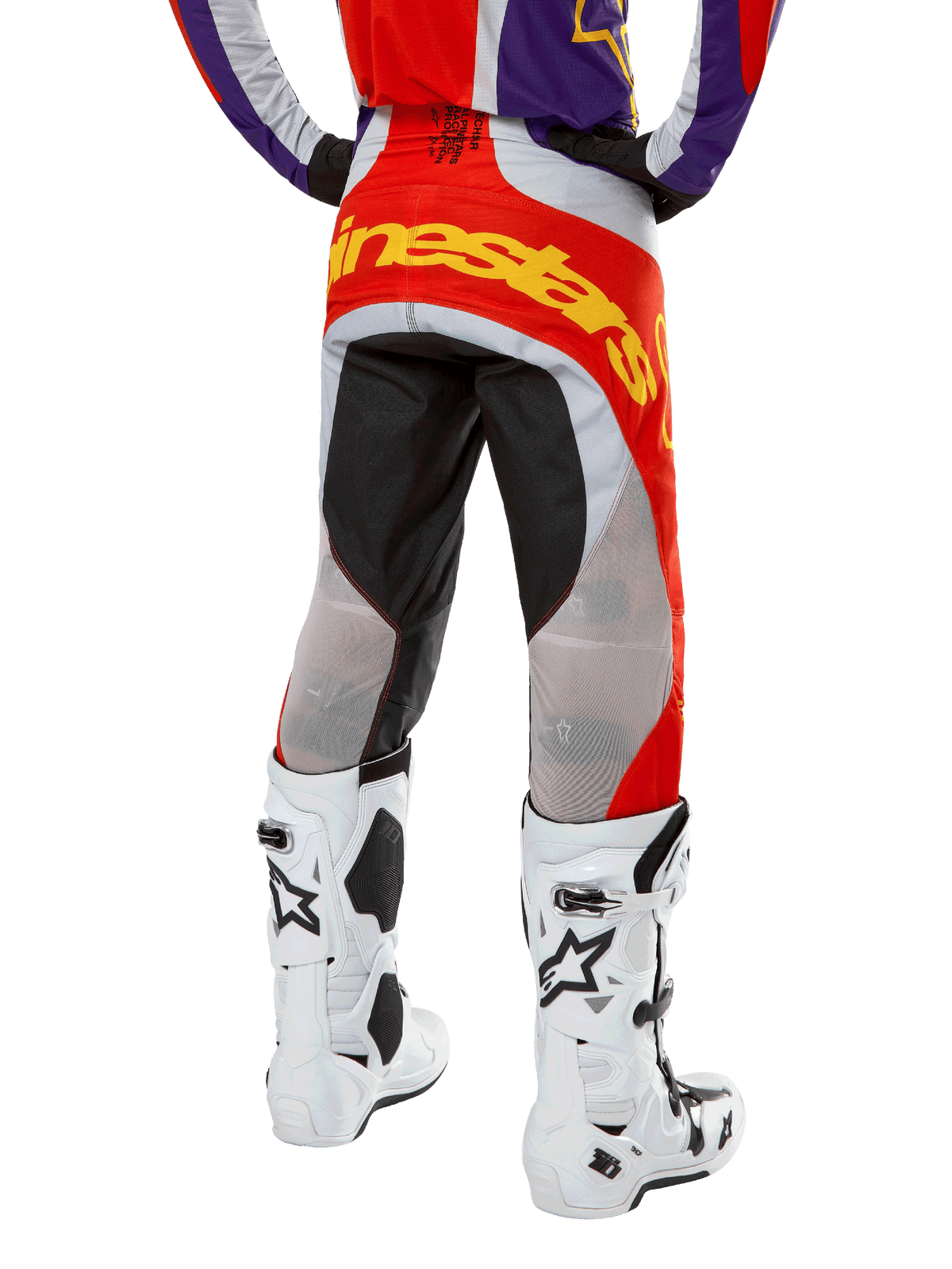 Alpinestars 2024 Techstar Ocuri Pants, Motocross Pants, Hot Orange Purple and Black, back view from the waist down, bold yellow branding across the seat, black and grey technical panels, paired with white motocross boots.