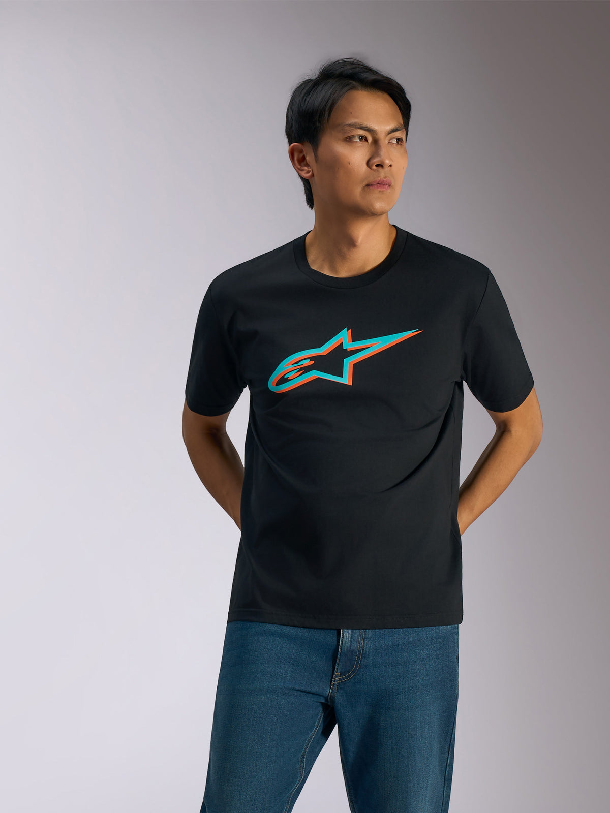 Alpinestars Ageless Shadow CSF Tee, Short Sleeve T-Shirt, Black with Turquoise and Orange Shadow Logo, worn by a man with blue jeans, Casual Motorsport Streetwear