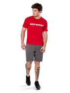 Alpinestars Linear Wordmark 2.0 CSF Tee, Short Sleeve T-Shirt, Red with white wordmark logo on chest, worn by model with grey shorts and black sneakers, casual motorsport-inspired streetwear