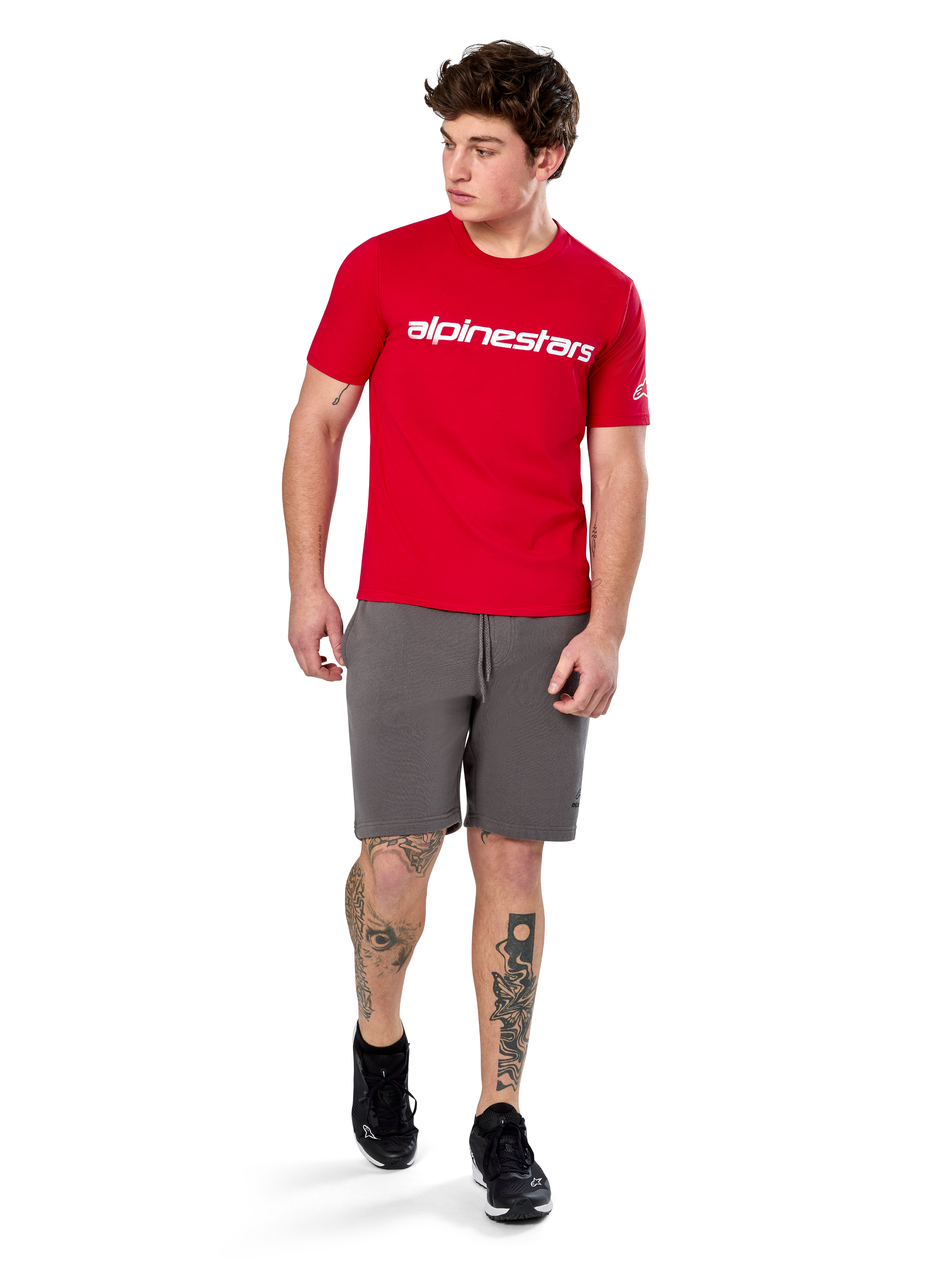 Alpinestars Linear Wordmark 2.0 CSF Tee, Short Sleeve T-Shirt, Red with white wordmark logo on chest, worn by model with grey shorts and black sneakers, casual motorsport-inspired streetwear