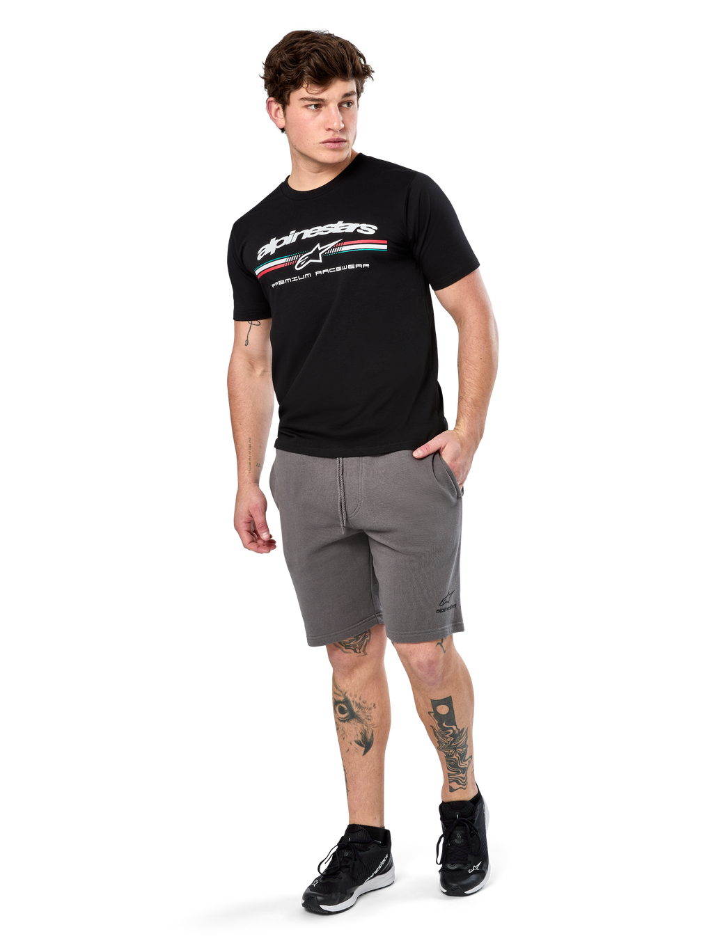 Alpinestars Prevail Csf Tee, Short Sleeve T-Shirt, Black, white Alpinestars logo with tri-color paddock stripe, worn with grey shorts and black sneakers, casual motorsport streetwear