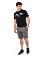 Alpinestars Prevail Csf Tee, Short Sleeve T-Shirt, Black, white Alpinestars logo with tri-color paddock stripe, worn with grey shorts and black sneakers, casual motorsport streetwear