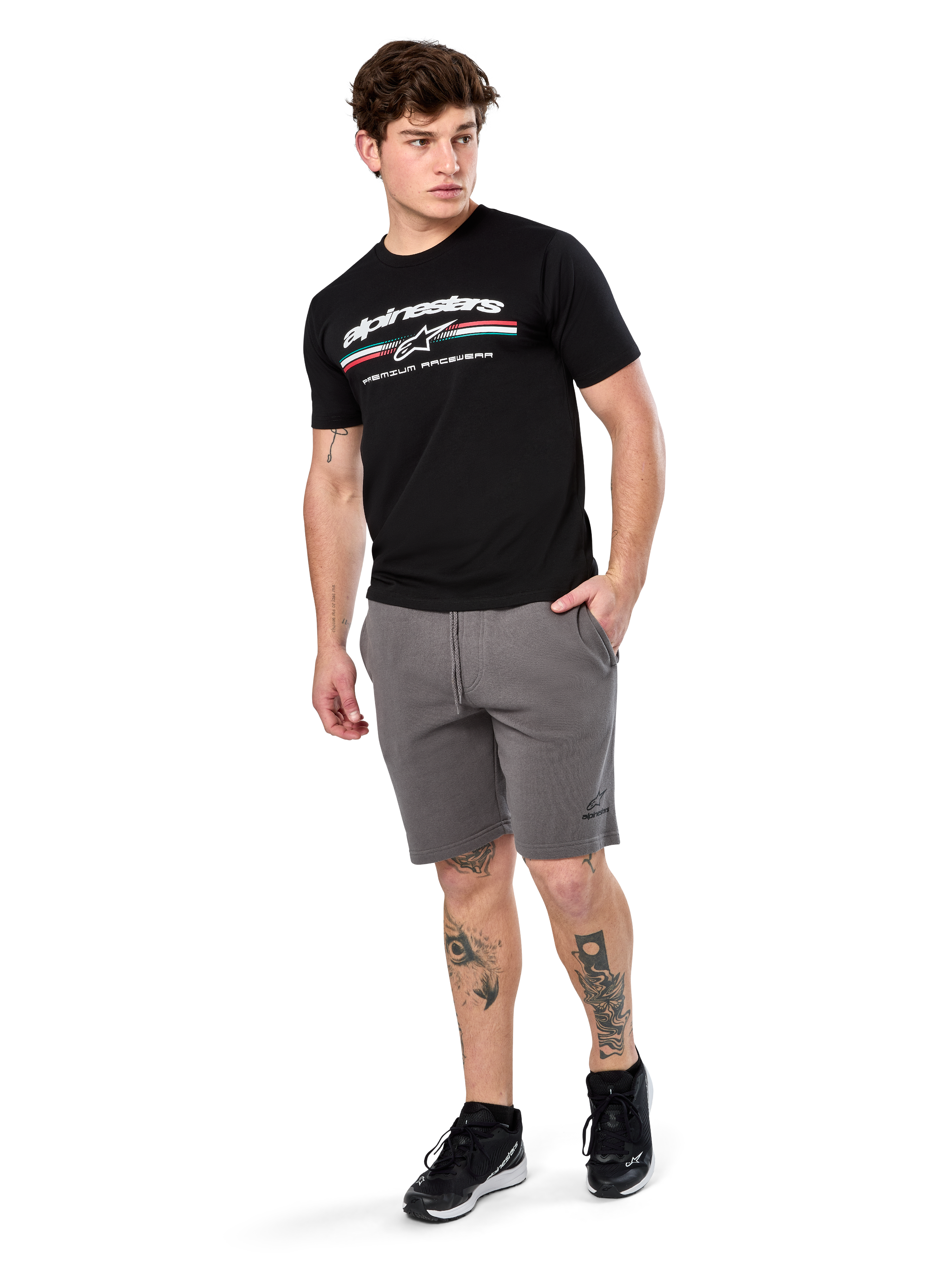 Alpinestars Prevail Csf Tee, Short Sleeve T-Shirt, Black, white Alpinestars logo with tri-color paddock stripe, worn with grey shorts and black sneakers, casual motorsport streetwear