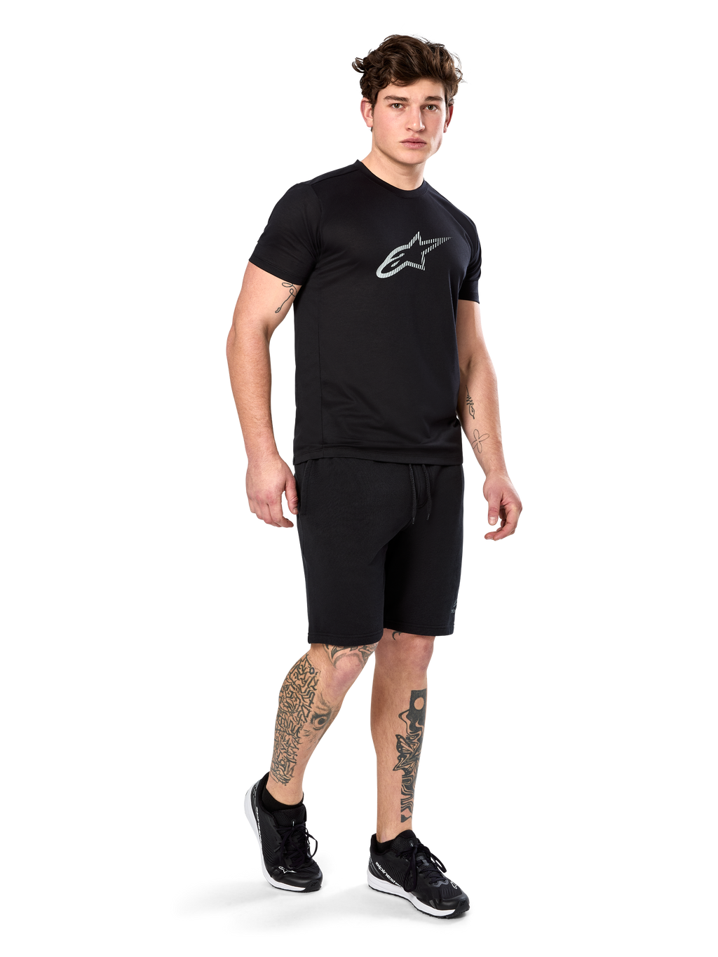 Alpinestars Exemption Performance Tee, Short Sleeve, Black, White Reflective Logo on Chest, worn with matching black shorts and sneakers, casual performance sportswear