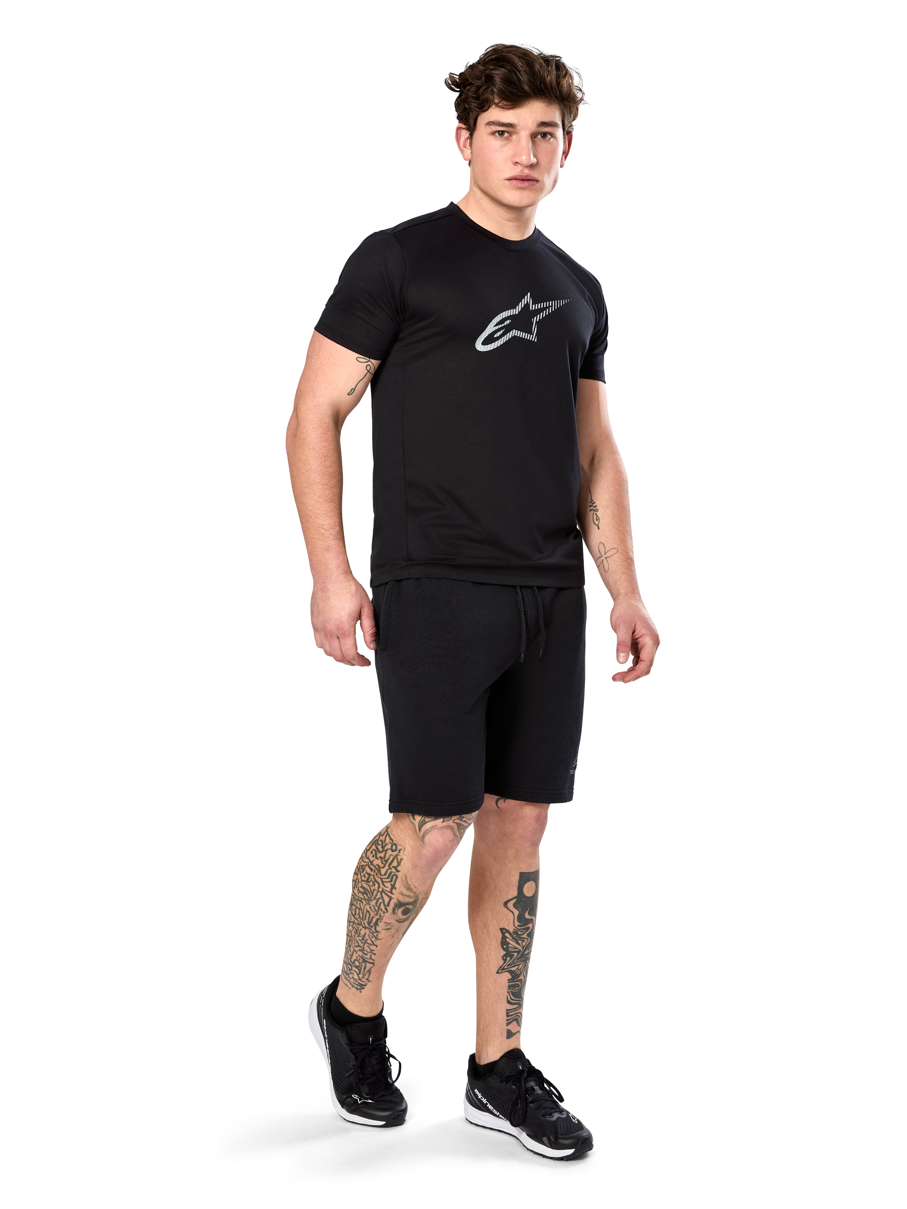 Alpinestars Exemption Performance Tee, Short Sleeve, Black, White Reflective Logo on Chest, worn with matching black shorts and sneakers, casual performance sportswear