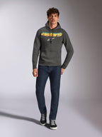 Alpinestars Ellipsoid Hoodie, casual sportswear, gunmetal gray with orange and yellow gradient Astars logo and white symbol, drawstring hood, worn by a male model with dark blue jeans and black sneakers, modern motorsport-inspired streetwear