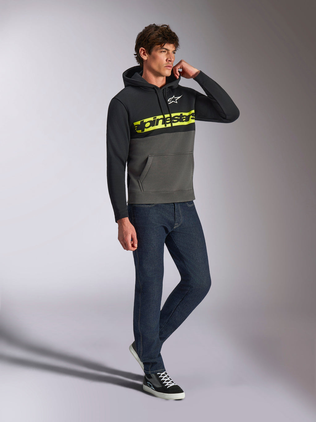 Alpinestars Parallel Hoodie, casual streetwear, color-blocked black and gunmetal grey, neon yellow Alpinestars word logo on chest, white Astars logo, drawstring hood, worn with dark jeans and sneakers