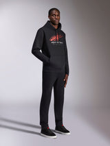 Alpinestars Pulse Hoodie, Black pullover hoodie, featuring red and white Astars logo with speed line fade and Racing Ahead text, worn with matching black trousers and sneakers, casual motorsport-inspired streetwear.