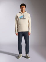 Alpinestars Pulse Hoodie, Off White, long sleeve pullover with drawstring hood, blue and black Astars Combo Logo with speed line fade, styled with dark jeans and sneakers, casual motorsport streetwear