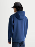 Alpinestars Cypher Hoodie, Steel Blue Sportswear Zip-Front Fleece, back view on model showing the high-neck mesh-lined hood and discreet Alpinestars logo on the lower back, premium tri-blend fabric for casual motorsport style.