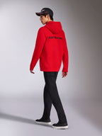 Alpinestars Transverse Hoodie, Red zip-up fleece hoodie, back view featuring black Alpinestars word logo, worn by a model with black pants and a black logo cap, casual motorsport-inspired streetwear