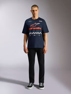 Alpinestars Aplomb Oversized CSF Tee, Short Sleeve Navy Blue T-Shirt, Large Chest Graphic with Orange and Red Gradient Logo and Checkered Pattern, worn by model with black pants and sneakers, Casual Motorsport Streetwear