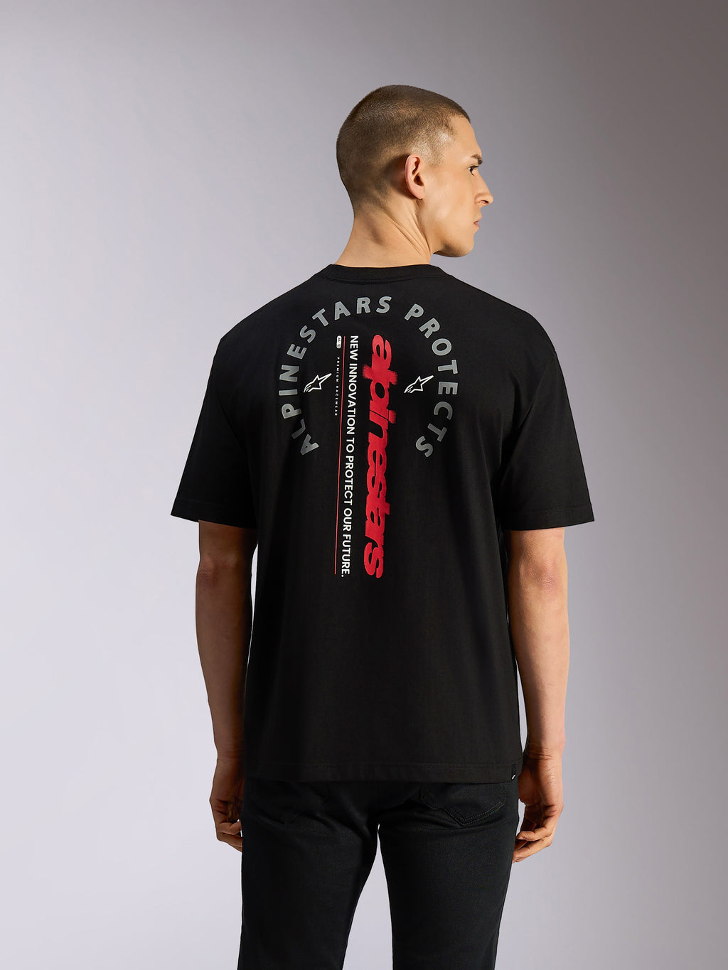 Alpinestars Overhang Oversized CSF Tee, Short Sleeve T-Shirt, Black, Back view showing vertical red Alpinestars wordmark and circular grey 'Alpinestars Protects' graphic, casual motorsport-inspired streetwear