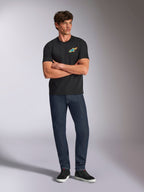 Alpinestars Angler CSF Tee, Short Sleeve T-Shirt, Black, Vibrant Multi-Color Astars Logo on Chest, worn by model with arms crossed, dark denim jeans and black sneakers, casual motorsport streetwear