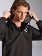 Alpinestars Speeder Chromium Windbreak Jacket, Black, worn by a male model holding the hood, features a white logo on the chest, mesh hood lining, and full-zip front, casual motorsport-inspired streetwear