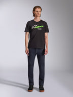 Alpinestars Entitled CSF Tee, Short Sleeve T-Shirt, Black, featuring a white star logo, neon green 'stars' text, and 'Racing Ahead' graphic on the chest, worn by a model with dark jeans, casual motorsport-inspired apparel
