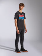 Alpinestars Harken CSF Tee, Short Sleeve T-Shirt, Black, Red White and Blue Racing Ahead graphic with Alpinestars branding, worn by a model with black pants and matching sneakers, casual motorsport streetwear