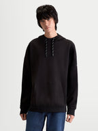 Alpinestars Camino Textured Oversized Hoodie, Black Premium Sportswear Pullover on model, featuring textured knit twill fleece, high collar with drawstrings, kangaroo pocket, and subtle embroidered logo.