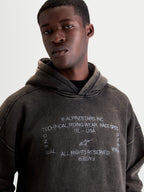 Alpinestars Infinite Washed Oversized Hoodie, Men's Casual Sportswear Pullover, Washed Black Snow-Wash Finish, Front view on model showing white embroidered chest graphic and relaxed fit.