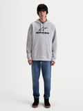 Alpinestars Prelude Oversized Hoodie, Men's Sportswear Fleece Pullover in Cement Gray. Features a relaxed fit with a black puff-print logo on the chest, a kangaroo pocket, and adjustable hood, shown on model with blue jeans.