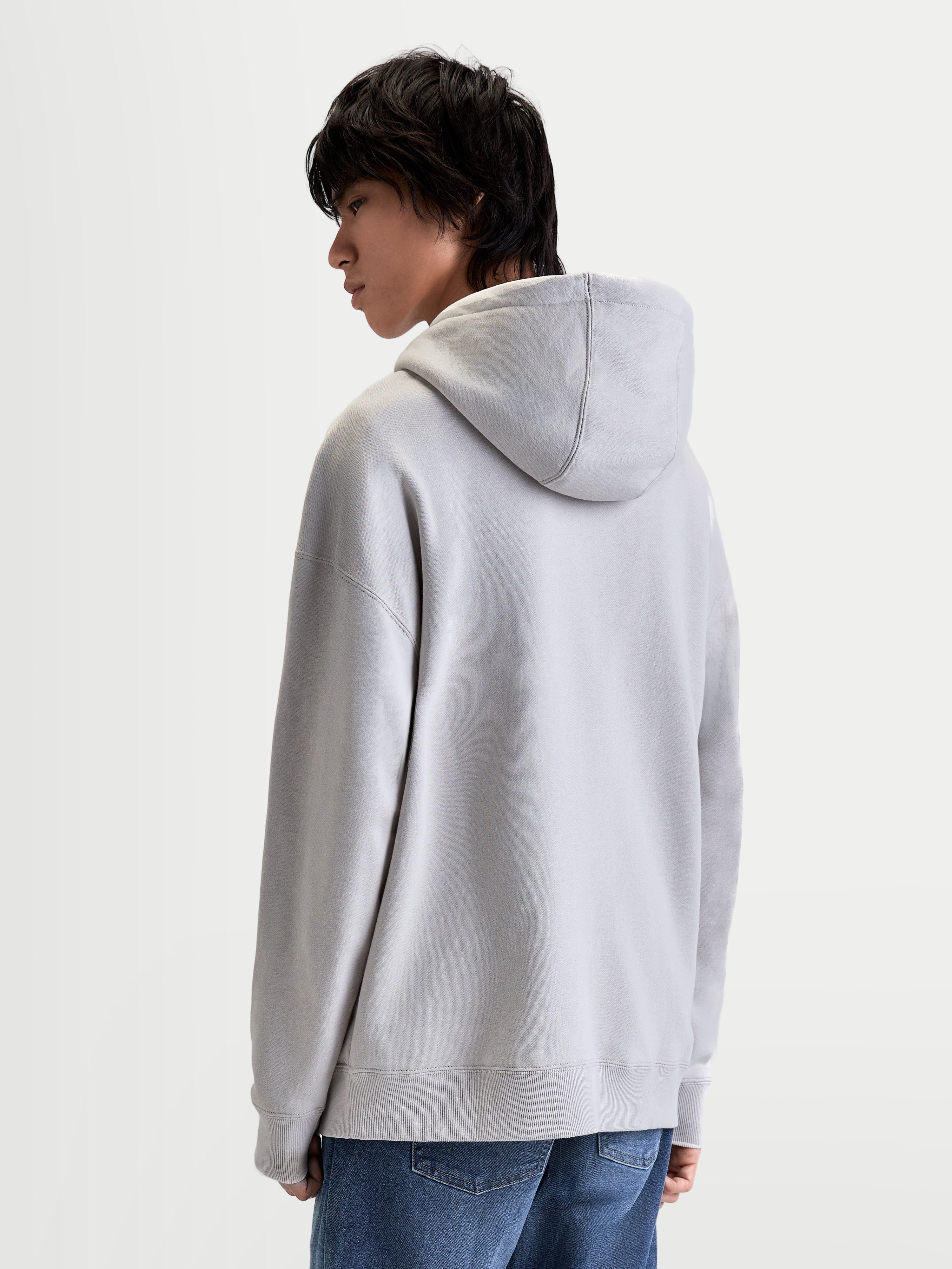 Alpinestars Prelude Oversized Hoodie, Sportswear Fleece Pullover for Men and Women, Cement Gray, featuring a relaxed silhouette, self-lined hood, and sleeve seaming, back view on model.