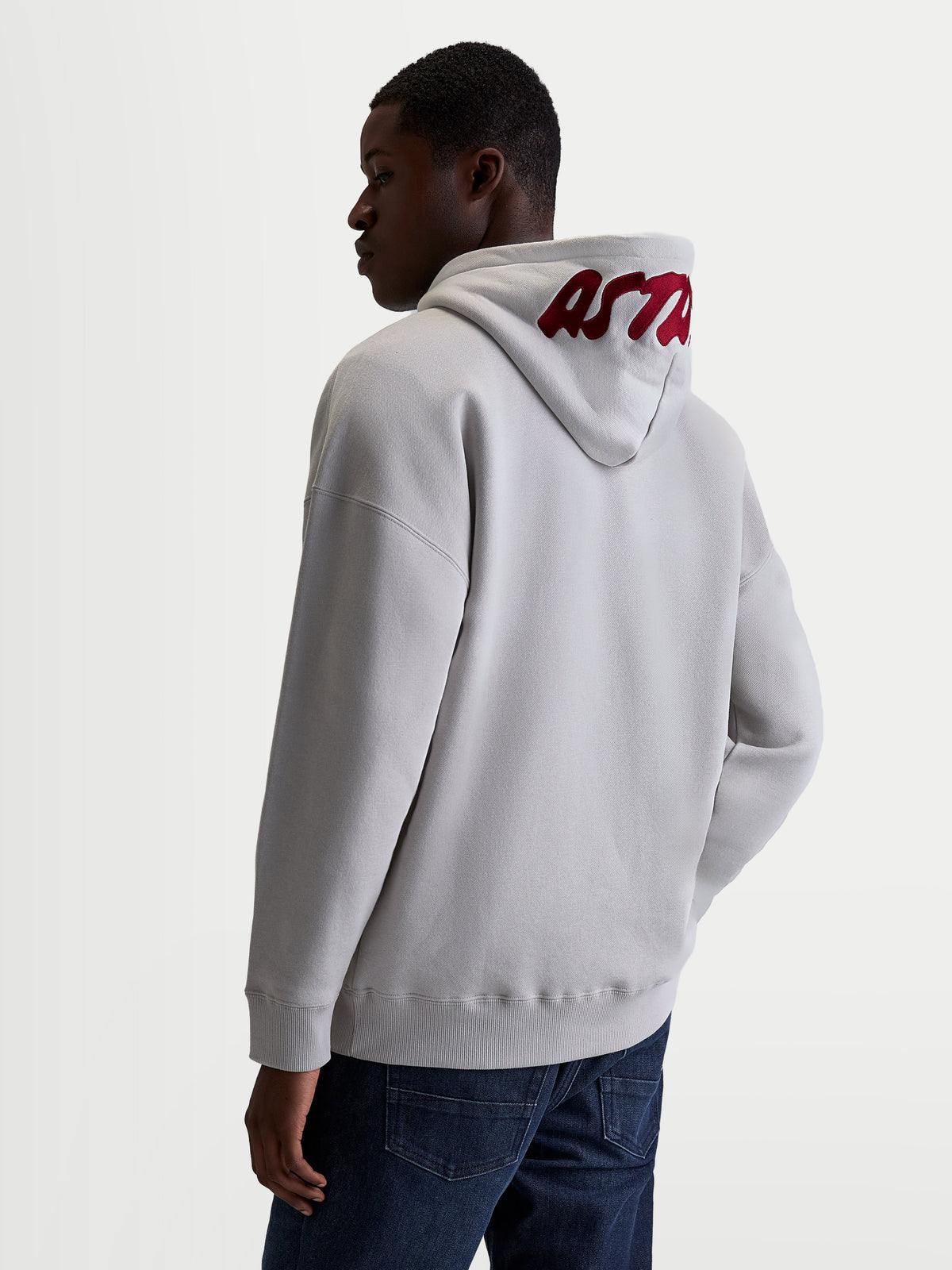 Alpinestars Pioneer Oversized Hoodie, Sportswear Zip Fleece, Unisex, Cement Gray and Red, features a relaxed oversized fit and premium red embroidered logo on the hood. Made from a soft cotton and recycled polyester blend for casual everyday comfort. Back view on model.