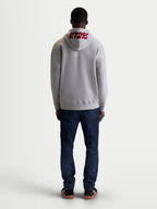Alpinestars Pioneer Oversized Hoodie, Casual Sportswear Zip Fleece for Men and Women, Cement Gray and Red, Rear view on model highlighting red 'ASTARS' embroidered logo on the hood and relaxed oversized fit.