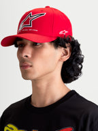 Alpinestars Lineout Hat, Red Sportswear Baseball Cap, on-model side profile view, featuring a curved bill and structured crown. Embroidered white and black Astars logos on the front and side with 'ONE GOAL. ONE VISION.' brand manifesto text. Durable red twill textile material for a casual motorsport-inspired look.