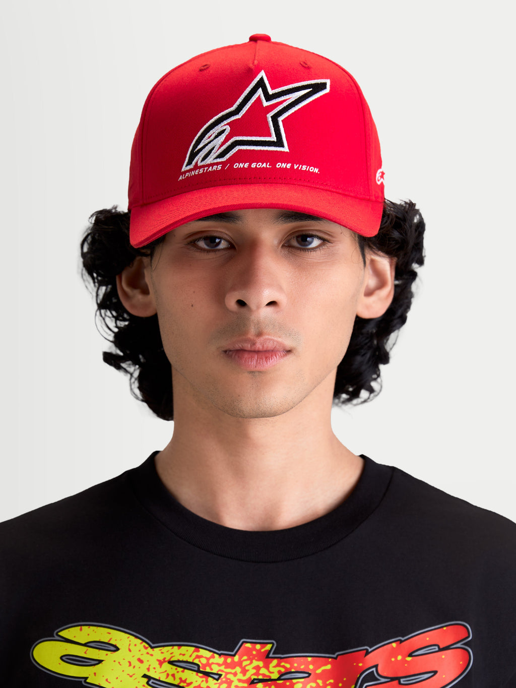 Alpinestars Lineout Hat, Red Curved Bill Baseball Cap, Sportswear Headwear for Men and Women, Red and White, featuring a structured crown and embroidered Astars logo with 'One Goal One Vision' slogan. Front view on model.