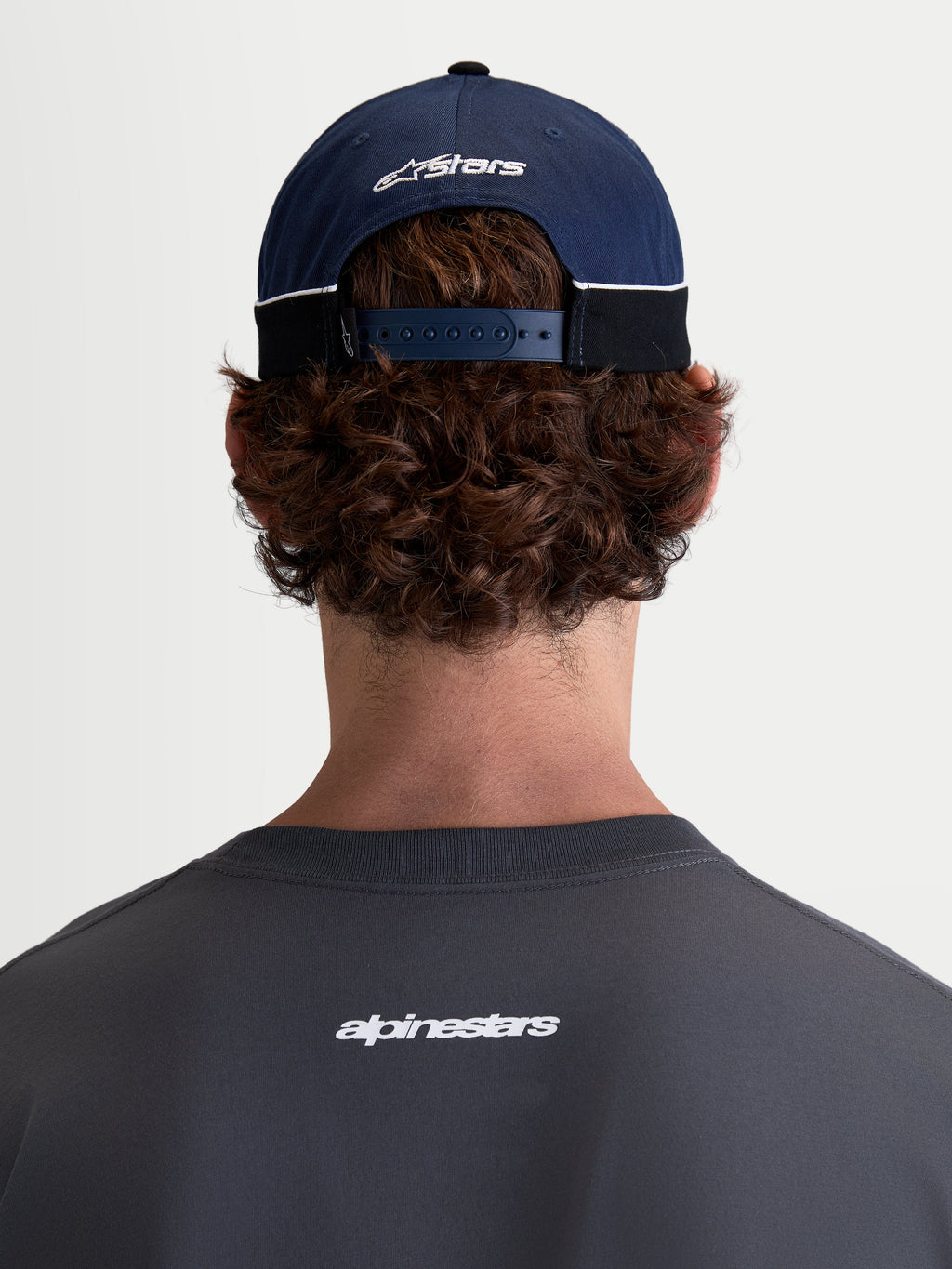 Alpinestars 500 Snapback Hat, Motorsport-inspired Sportswear Baseball Cap, Navy Blue and Black, 100% Cotton Twill construction with an adjustable snapback closure and embroidered Astars logo, rear view on model.