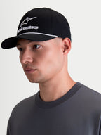 Alpinestars Combo Logo Snapback Hat, Black and White Sportswear Lifestyle Cap, featuring a curved bill, structured crown, white Alpinestars combo logo embroidery and rope trim detail, shown on-model in a profile view.