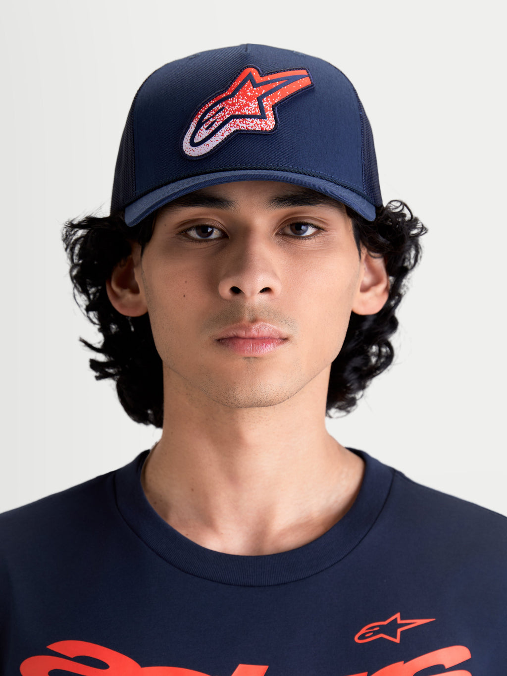 Alpinestars Meteorite Trucker Hat, Sportswear Mesh Back Cap for Men and Women, Navy Blue with Red and White Astars Gravel Texture Logo, Structured Crown, Curved Bill, Front View on Model