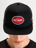 Alpinestars Hotlink Trucker Hat, motorsport sportswear snapback cap, black, flat bill and structured crown featuring a red and white Astars woven logo patch with bike chain border, front view worn on a model