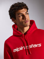 Alpinestars Linear Wordmark V3 Hoodie, red casual pullover fleece, white Alpinestars wordmark on chest, drawstring hood with dipped tips, lifestyle shot of male model