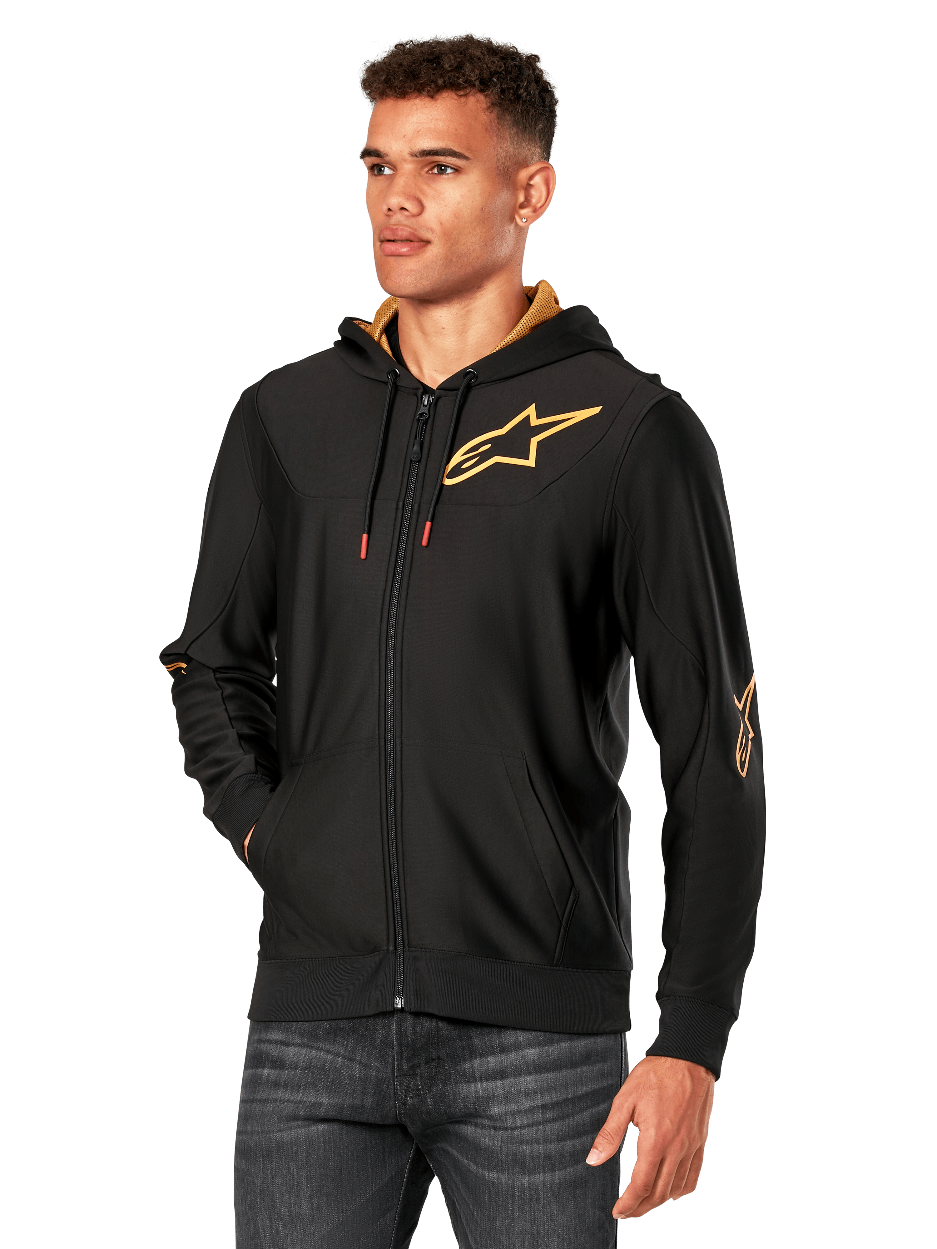 Alpinestars Sessions V3 Hoodie, Black with Gold logos, zip-up fleece hoodie worn by a model with dark jeans, featuring a gold mesh-lined hood and red-tipped drawcords, casual motorsport-inspired streetwear