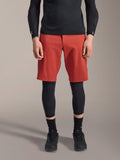 Alpinestars A-Motion Plasma Knee Sleeve, Black MTB knee protector, worn with red shorts and black long-sleeve top, slim-profile ergonomic design, lightweight mesh construction for off-road riding