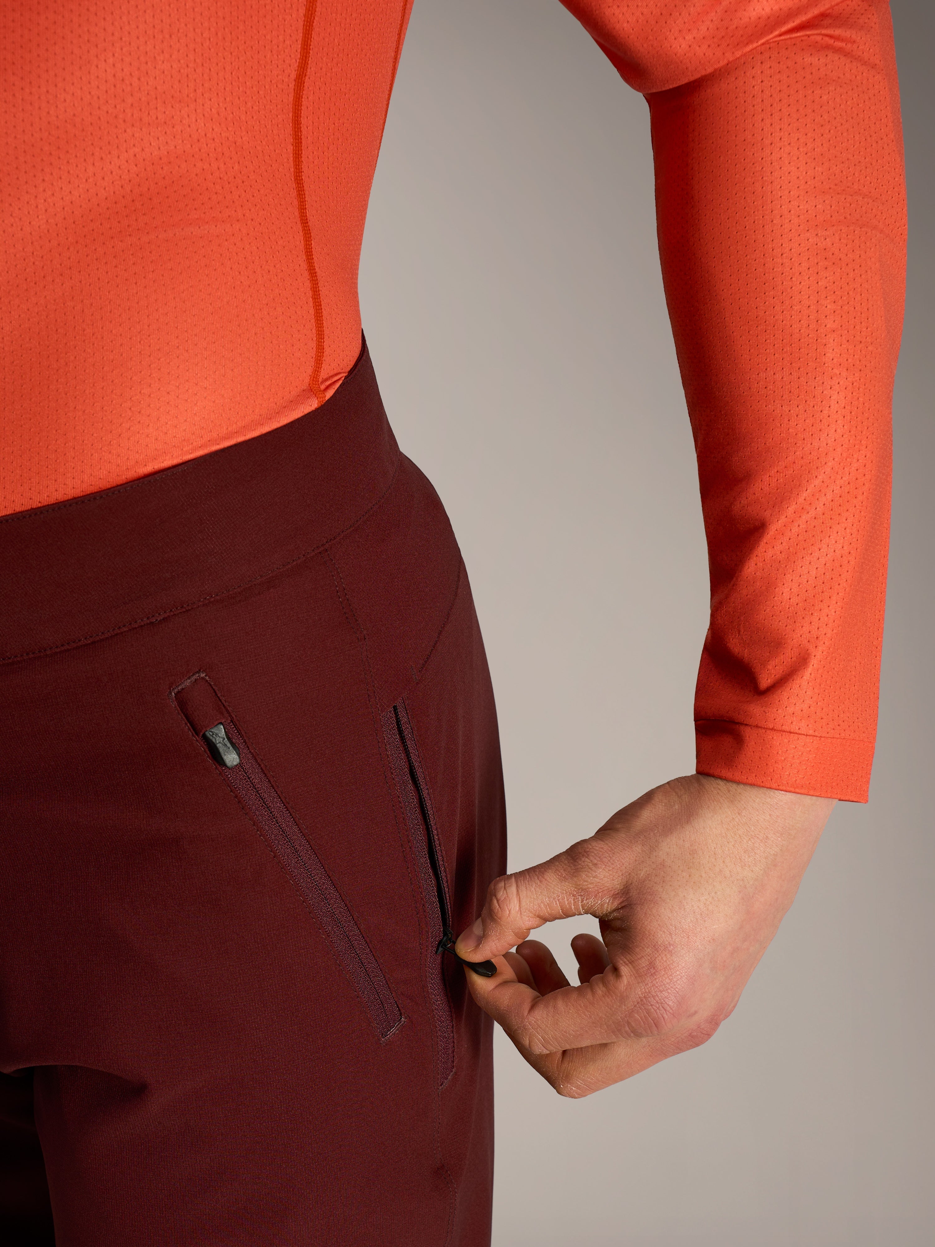 Alpinestars A-Dura Ride Shorts in bordeaux, detail of a hand opening the secure zippered mesh-lined side pocket.