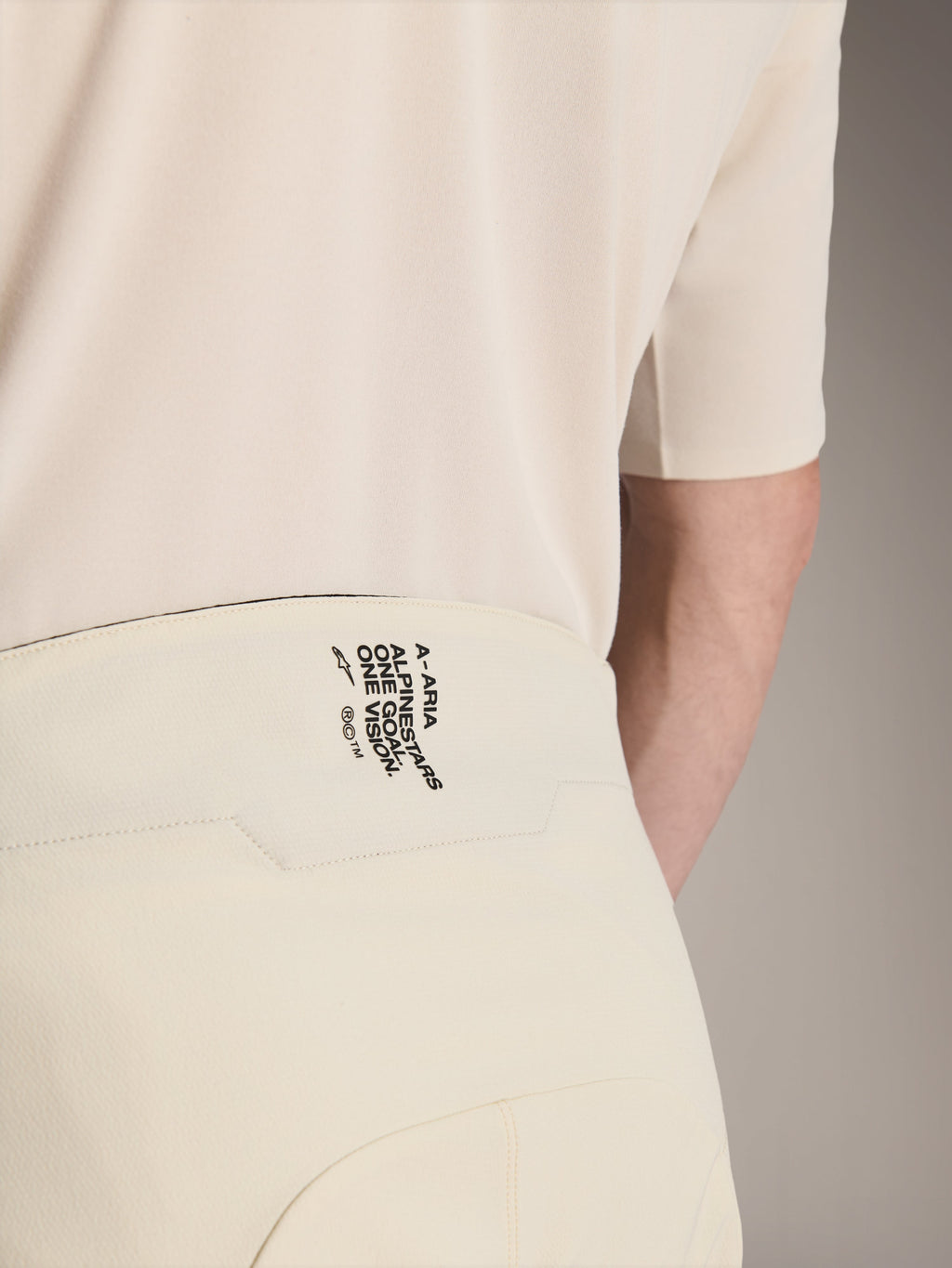 Alpinestars A-Aria Elite Shorts, Mountain Bike Shorts, Ecru color, close-up of the back waistband featuring black branding 'A-ARIA ALPINESTARS ONE GOAL. ONE VISION.', performance cycling apparel