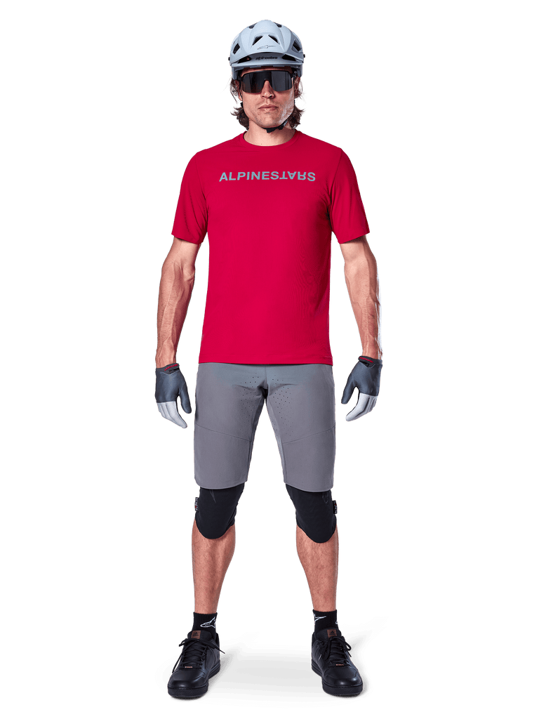 Alpinestars A-Aria Elite Shorts, Men's MTB Cycling Shorts in Dark Gray, with flexible stretch fabric and a red racing jersey.