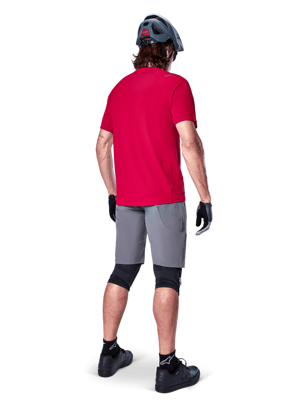 Alpinestars A-Aria Elite Shorts, dark gray men's mountain bike shorts, rear view on a rider with a red jersey.