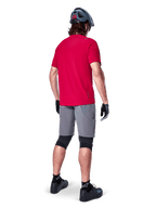 Alpinestars A-Aria Elite Shorts, dark gray men's mountain bike shorts, rear view on a rider with a red jersey.