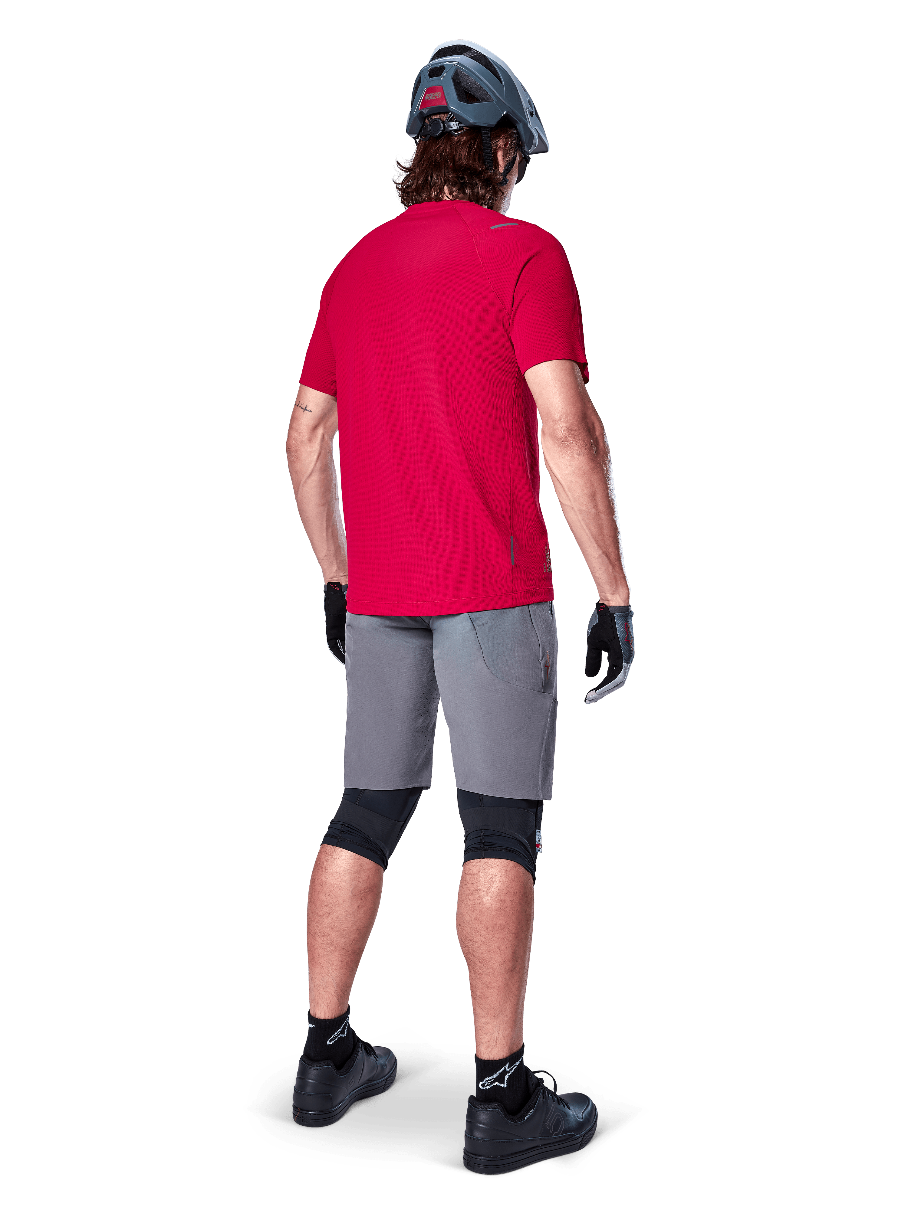 Alpinestars A-Aria Elite Shorts, dark gray men's mountain bike shorts, rear view on a rider with a red jersey.
