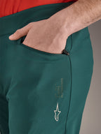 Alpinestars A-Dura Pants in Dark Pine green, close-up of zippered pocket with hand, featuring white Alpinestars logo and text branding on the thigh, durable MTB cycling trousers